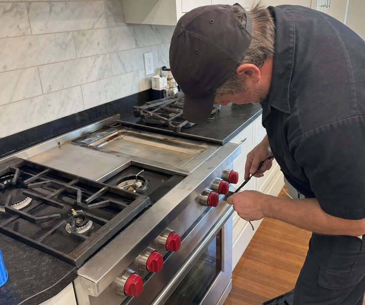 Technician servicing a stainless Wolf range in an Armonk kitchen